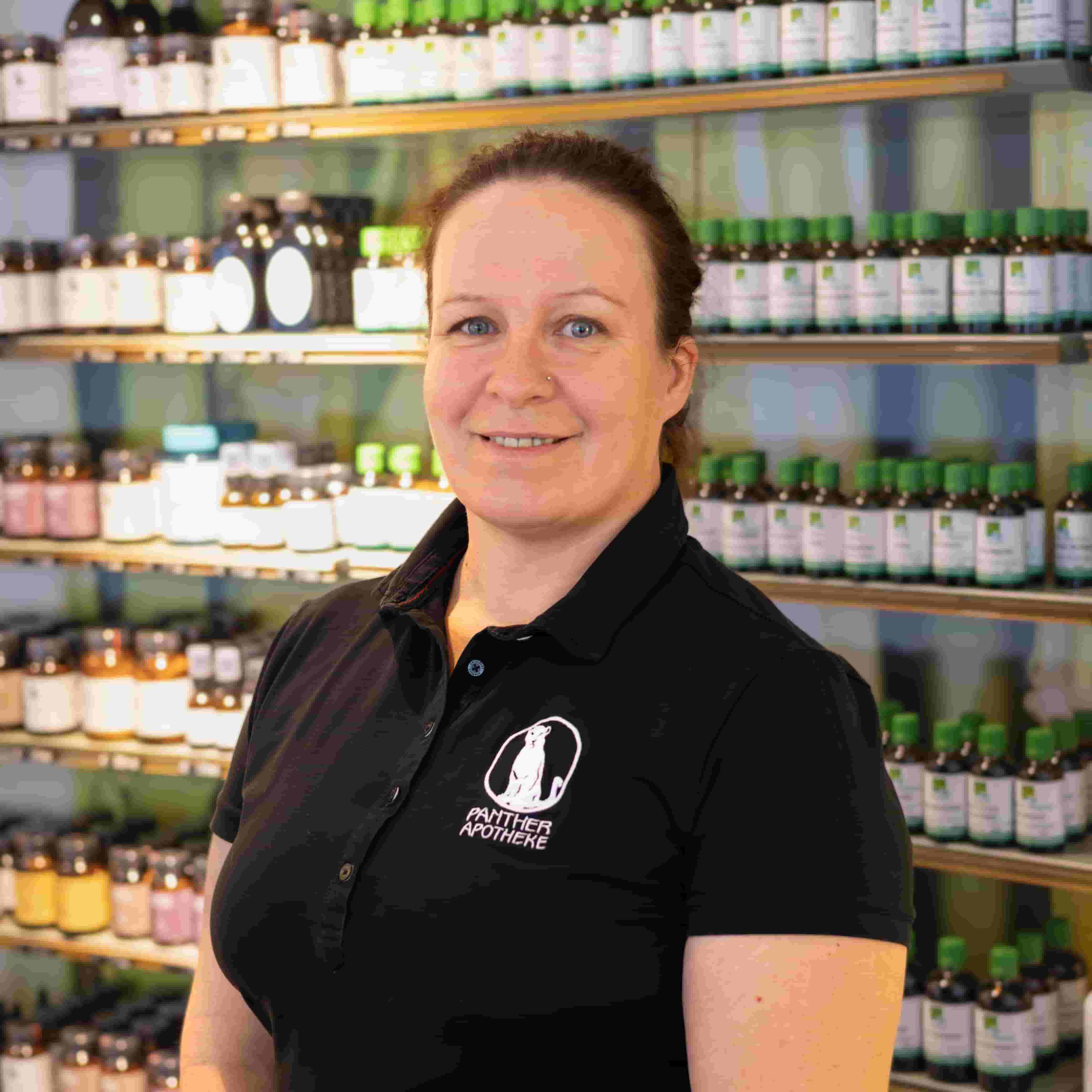 Porträt von Karin Obruca, stehend vor einem Produktregal.